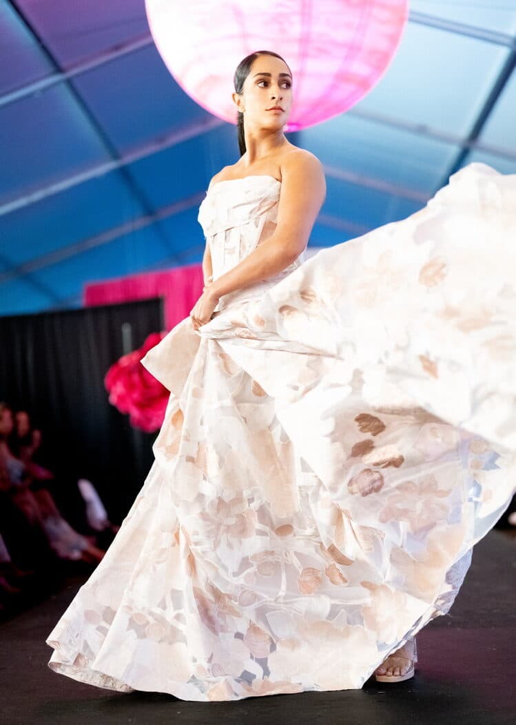Model on the runway in a strapless ivory organza gown with painted floral panels